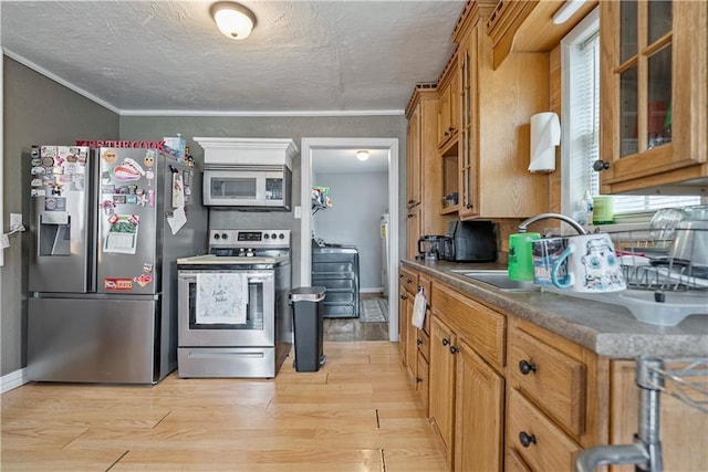 kitchen with light wood-style flooring, ornamental molding, brown cabinets, appliances with stainless steel finishes, and glass insert cabinets