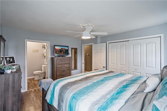 bedroom with a closet, wood finished floors, ensuite bathroom, baseboards, and ceiling fan