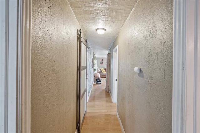 hall featuring light wood-style floors and a textured wall