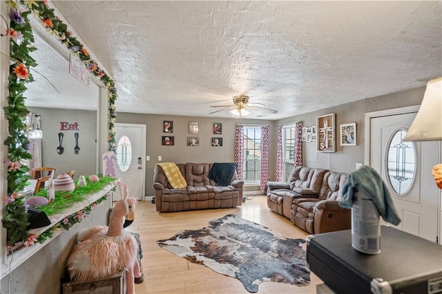 living room with a textured ceiling, ceiling fan, and wood finished floors
