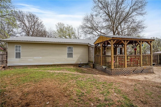 rear view of house featuring metal roof, fence, a gazebo, and a yard