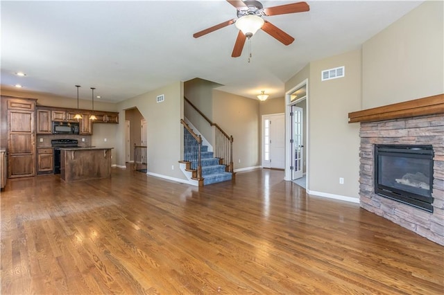 17281 S Kimble St, Olathe, KS 66062 - unfurnished living room featuring stairway, wood finished floors, a stone fireplace, and a ceiling fan