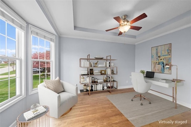 home office featuring a healthy amount of sunlight, a raised ceiling, and light wood-style floors