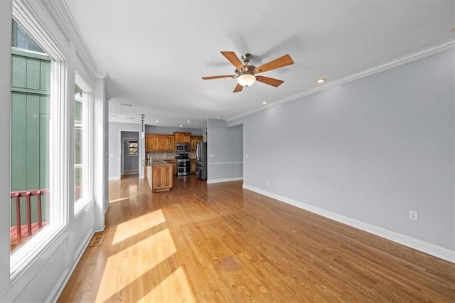 unfurnished living room with ornamental molding, ceiling fan, and a healthy amount of sunlight