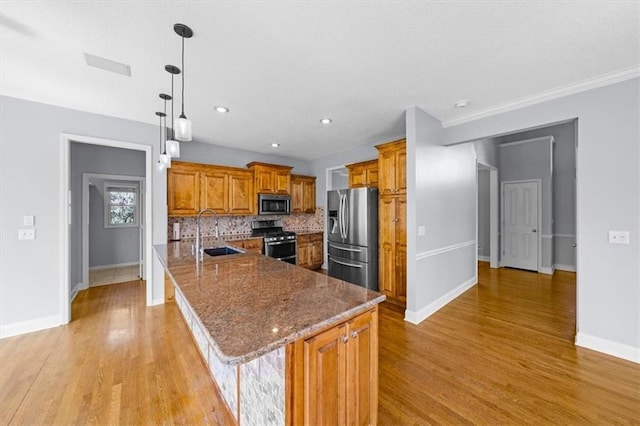 kitchen with brown cabinetry, light wood-type flooring, a sink, baseboards, and stainless steel appliances