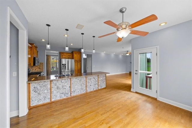 kitchen featuring brown cabinetry, baseboards, ceiling fan, and stainless steel appliances