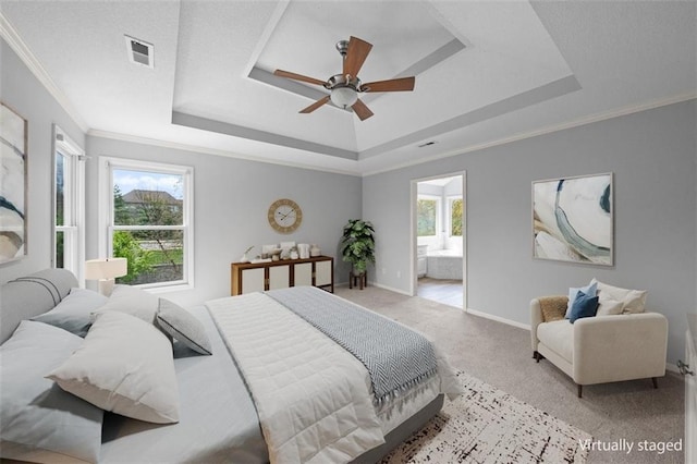 bedroom with connected bathroom, light colored carpet, baseboards, a tray ceiling, and visible vents