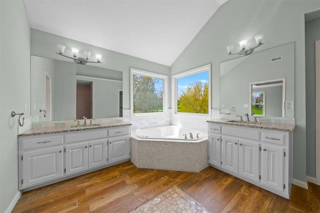 bathroom with a sink, two vanities, lofted ceiling, and visible vents