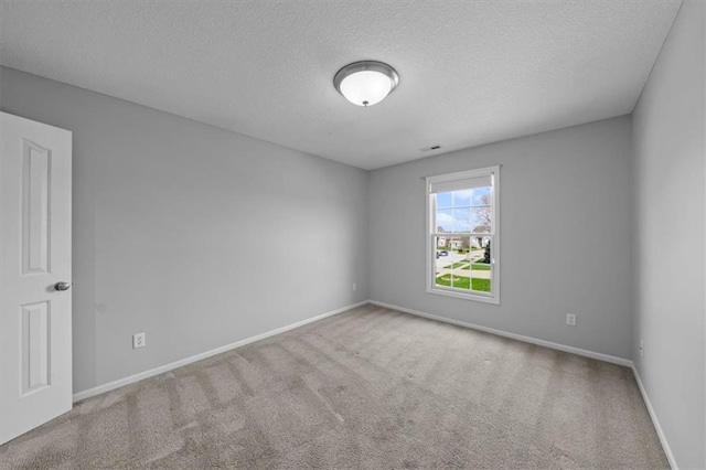 spare room with baseboards, carpet flooring, and a textured ceiling