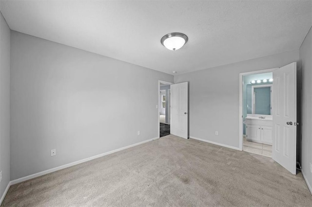 unfurnished bedroom with carpet flooring, baseboards, and ensuite bath