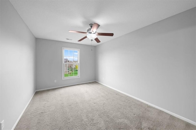 carpeted empty room featuring a ceiling fan, baseboards, and visible vents