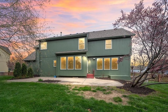 back of house with fence, a patio, a yard, and roof with shingles