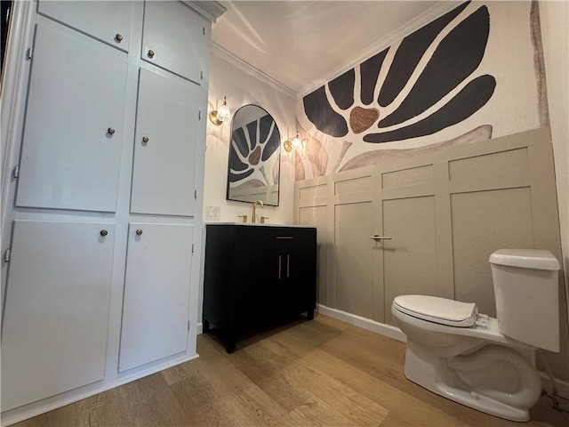 bathroom featuring toilet, wood finished floors, vanity, and crown molding