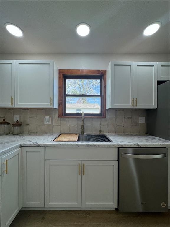 kitchen featuring white cabinets, stainless steel dishwasher, decorative backsplash, and a sink