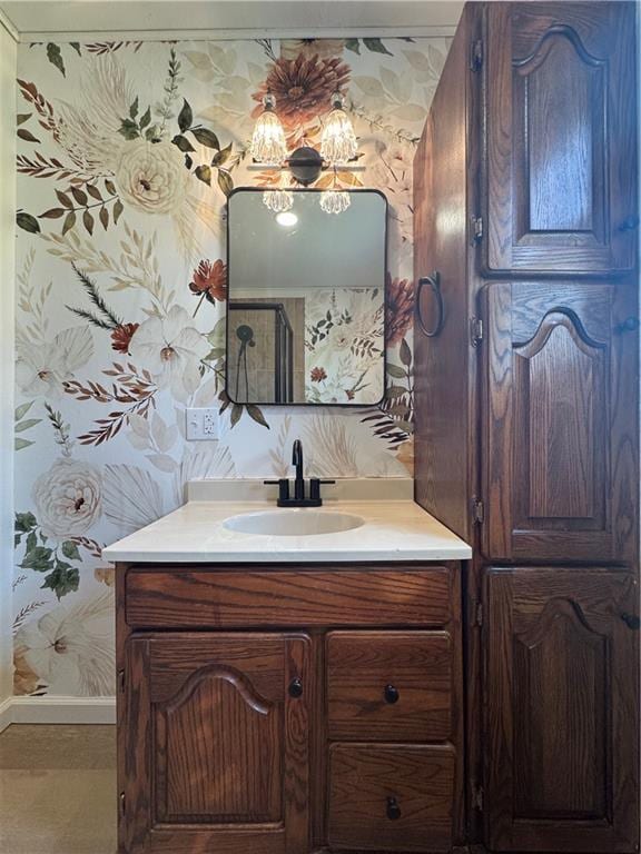 bathroom featuring baseboards, vanity, and wallpapered walls