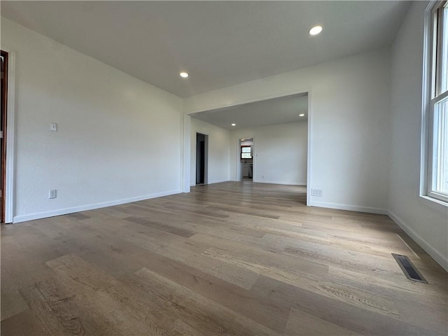 spare room featuring a wealth of natural light, wood finished floors, visible vents, and baseboards