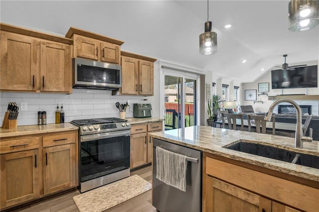 900 NW Lindenwood Dr, Grain Valley, MO 64029 - kitchen with stainless steel appliances, vaulted ceiling, decorative backsplash, light wood-type flooring, and a sink