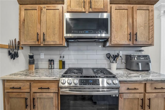 900 NW Lindenwood Dr, Grain Valley, MO 64029 - kitchen with appliances with stainless steel finishes, tasteful backsplash, and light stone counters