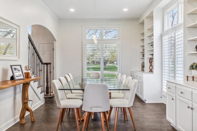 dining space featuring crown molding, arched walkways, dark wood finished floors, built in shelves, and stairway