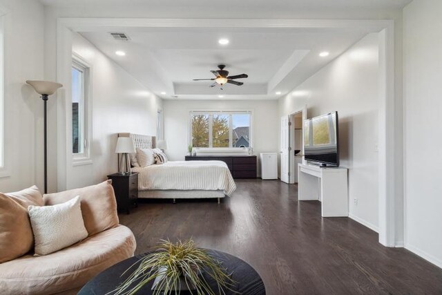bedroom with a raised ceiling, recessed lighting, baseboards, visible vents, and dark wood-style floors