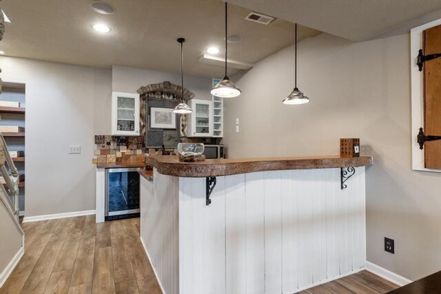 kitchen featuring visible vents, wine cooler, a kitchen bar, recessed lighting, and light wood finished floors