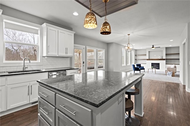 7295 NW Forest Lakes Dr, Parkville, MO 64152 - kitchen featuring a kitchen island, a breakfast bar area, dishwasher, white cabinetry, and decorative light fixtures