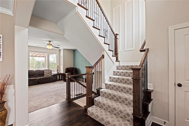 staircase featuring baseboards, a ceiling fan, and hardwood / wood-style flooring