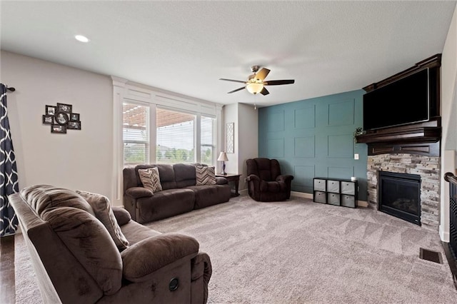 carpeted living room with ceiling fan, a fireplace, and visible vents