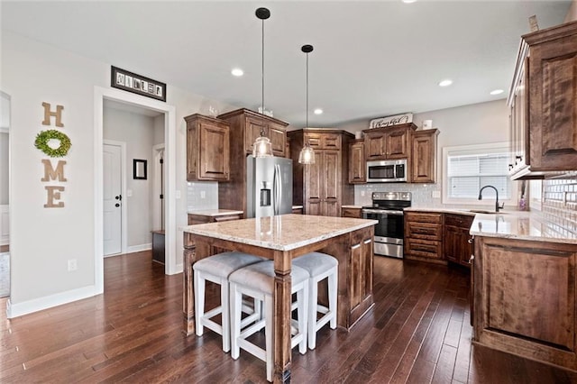 kitchen with a kitchen breakfast bar, stainless steel appliances, decorative backsplash, a kitchen island, and dark wood-style floors