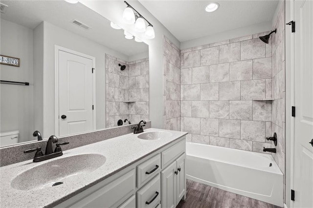 bathroom featuring visible vents, a sink, wood finished floors, and double vanity