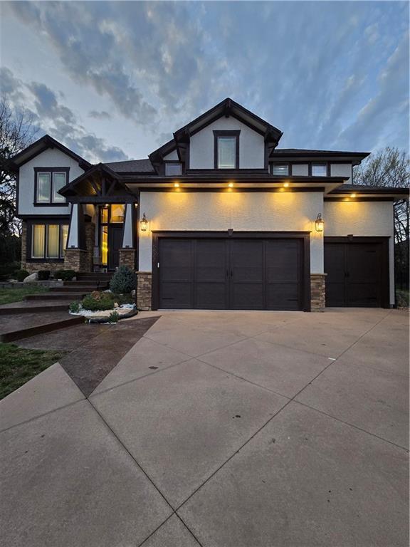 prairie-style house with stone siding, driveway, and a garage