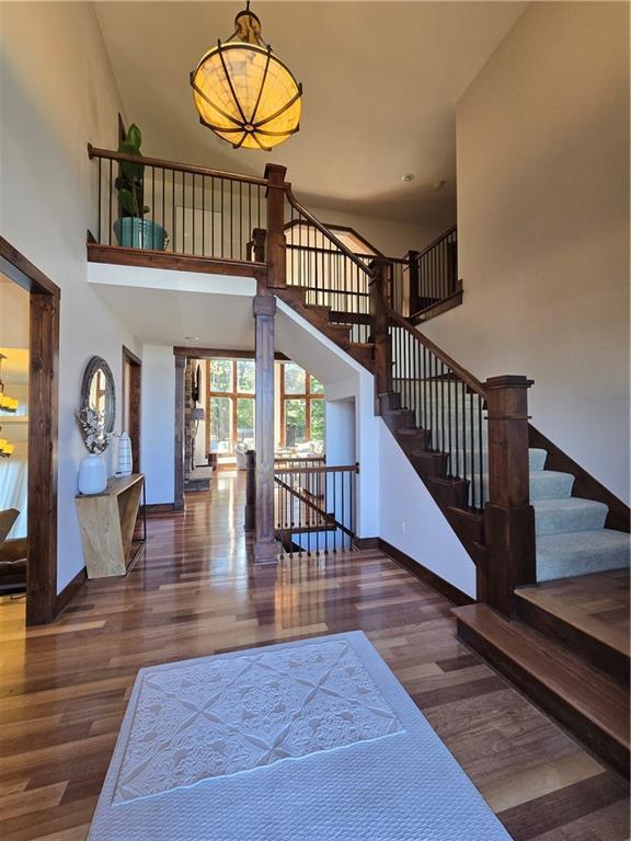 interior space with a high ceiling, baseboards, stairs, and wood finished floors