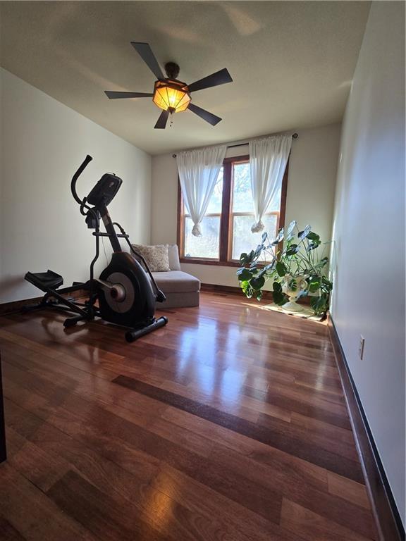 exercise room featuring a ceiling fan, baseboards, and wood finished floors