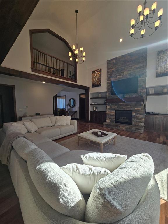 living area with a high ceiling, a fireplace, wood finished floors, and a chandelier
