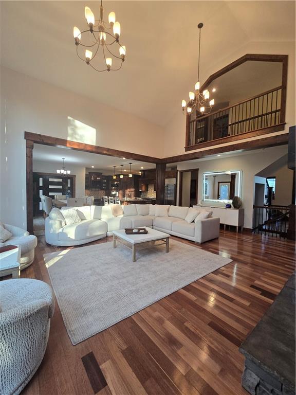 living room with high vaulted ceiling, wood finished floors, and a chandelier