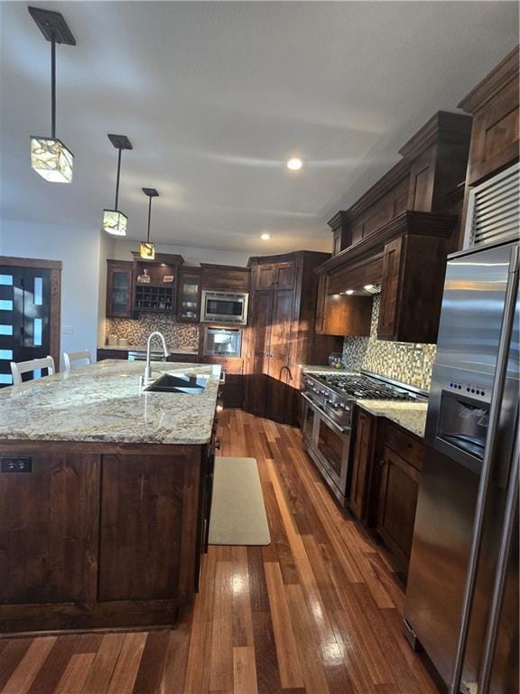 kitchen with a sink, tasteful backsplash, appliances with stainless steel finishes, and dark wood finished floors