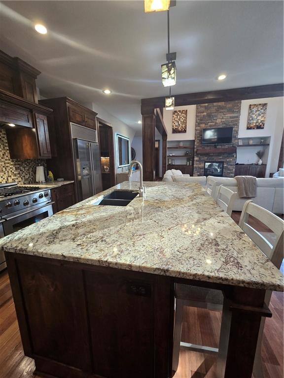 kitchen featuring stainless steel range with gas stovetop, dark brown cabinets, high quality fridge, a sink, and a spacious island