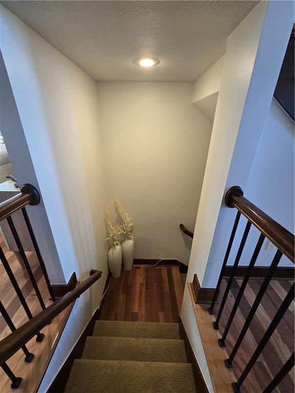 staircase with a textured ceiling and wood finished floors
