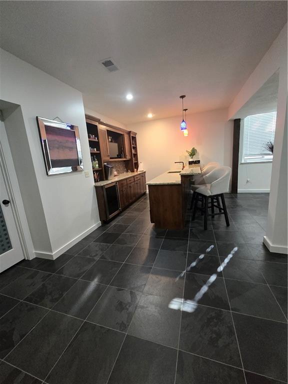kitchen with light countertops, pendant lighting, a breakfast bar, baseboards, and visible vents