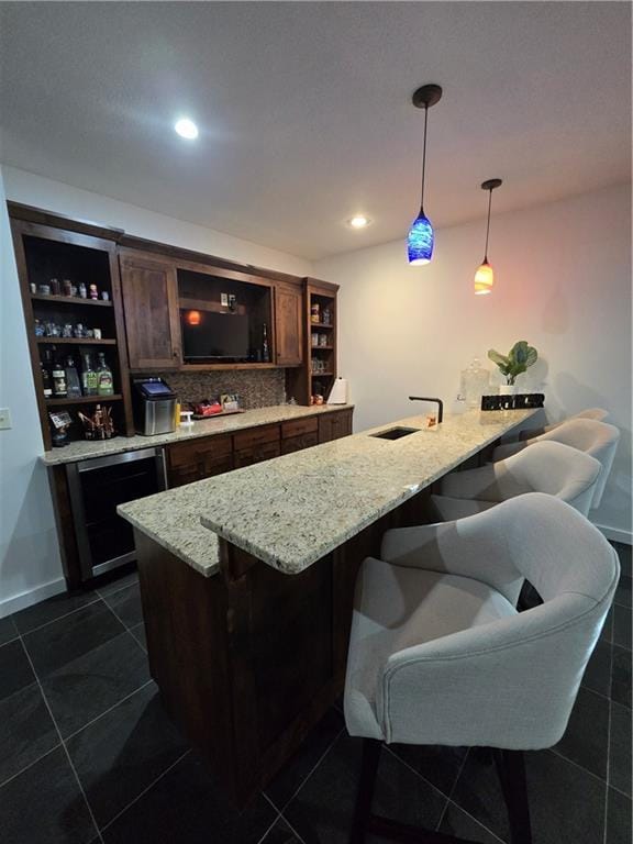 bar with a sink, indoor wet bar, dark tile patterned floors, and pendant lighting