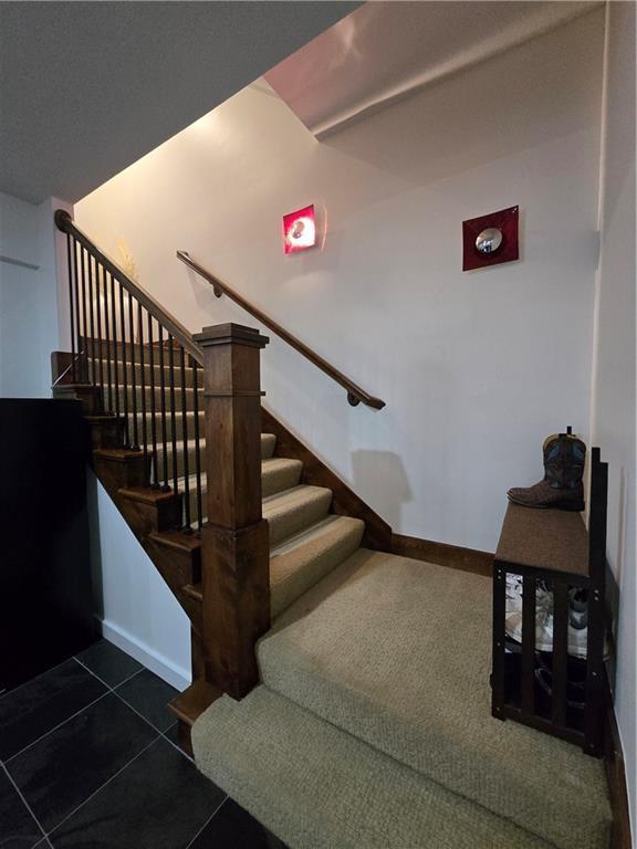 stairway with tile patterned floors and baseboards