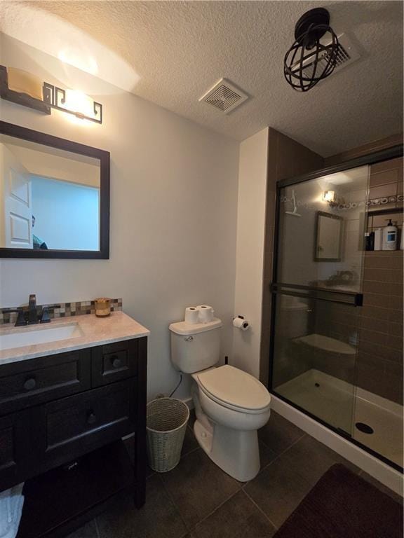 full bathroom featuring tile patterned floors, toilet, vanity, a shower stall, and visible vents