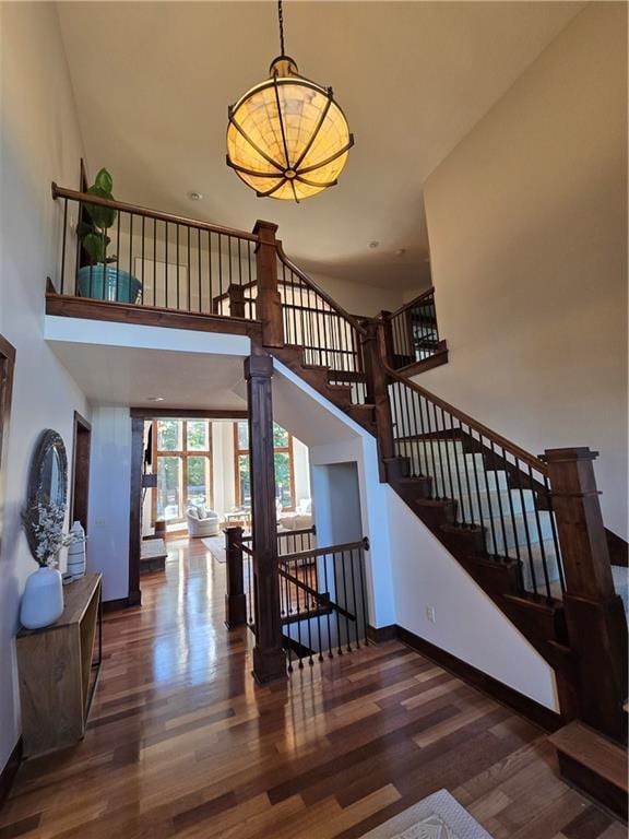 stairs featuring a towering ceiling, baseboards, a chandelier, and wood finished floors