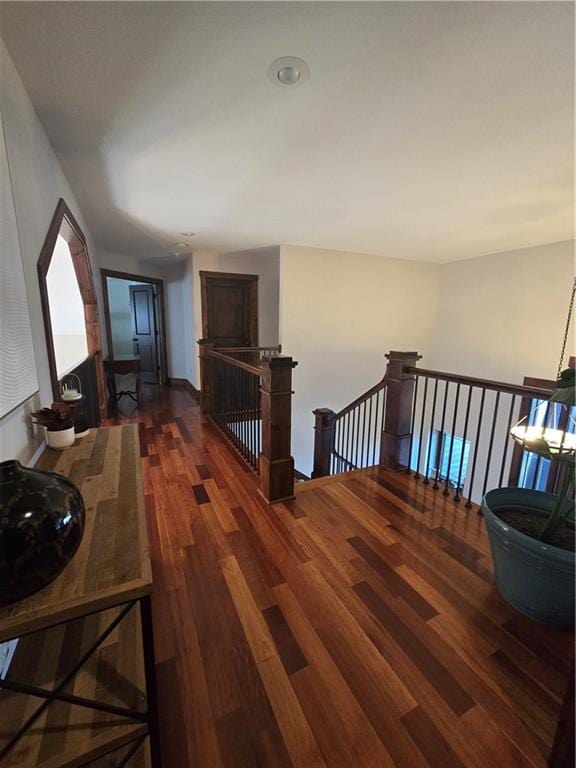 hall with a sink, an upstairs landing, and dark wood-style floors