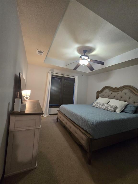 bedroom featuring visible vents, a textured ceiling, dark carpet, and a ceiling fan