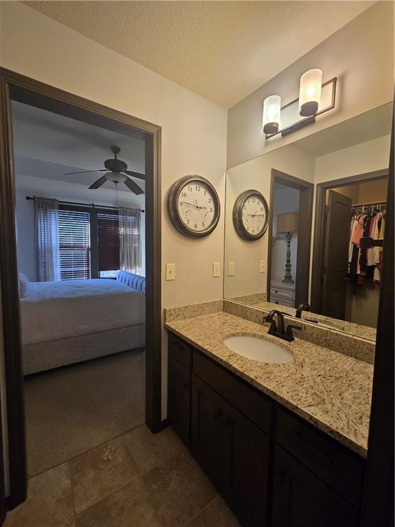 bathroom featuring vanity, a spacious closet, a textured ceiling, a ceiling fan, and ensuite bathroom