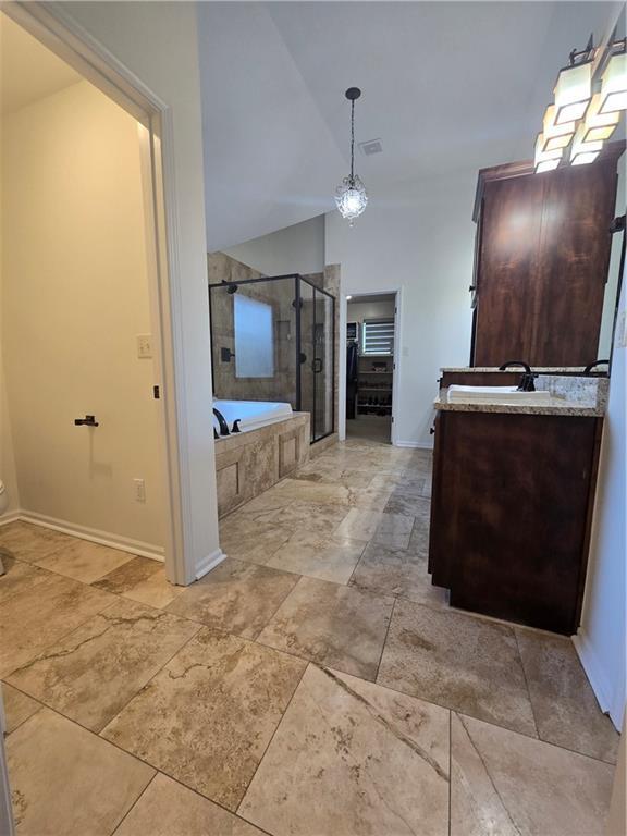 full bathroom with baseboards, vanity, lofted ceiling, a stall shower, and a garden tub