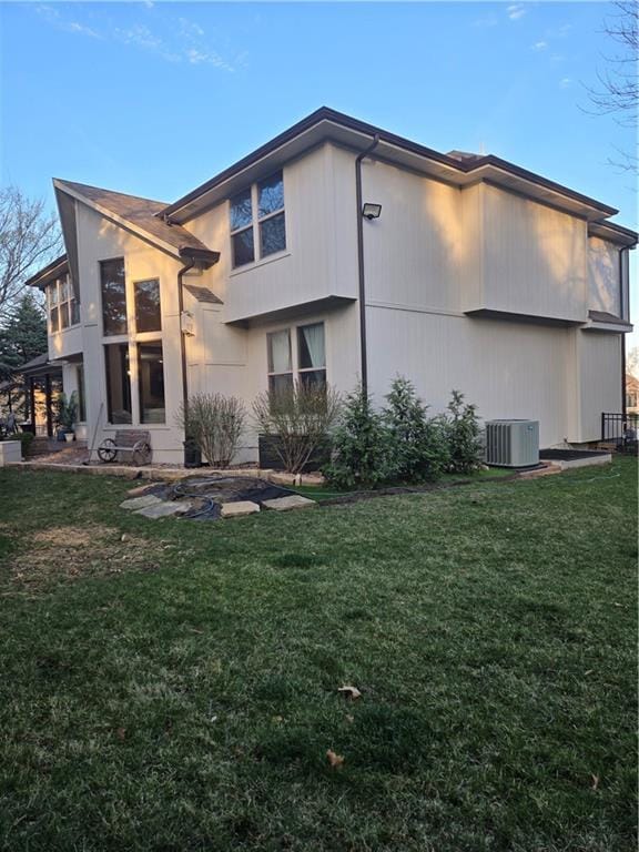 back of property featuring central AC unit and a lawn