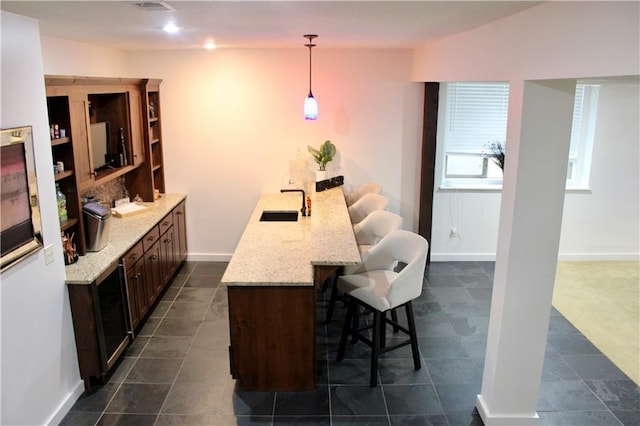 6822 Woodstock Ct, Shawnee, KS 66218 - kitchen with a breakfast bar, light stone countertops, pendant lighting, dark brown cabinets, and a peninsula