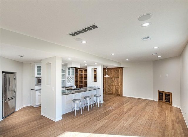 kitchen featuring visible vents, light wood-style flooring, a kitchen bar, and stainless steel appliances